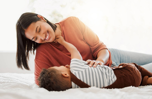 Happy, love and family time with a mother and son being playful and bonding on a bed at home. Parent playing with her child, smiling and enjoying motherhood. Single mom embracing her son - Foto, Bild