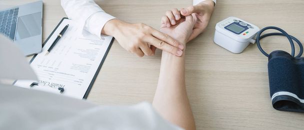 The doctor examines the patient's pulse by hand and records the results, health medical checkup concept. - Foto, Imagem