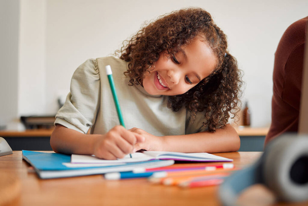 Learning, smiling and creative young girl drawing with a colorful pencil feeling happy and content. Positive student with a smile having a fun time creating artistic art in her kids notebook at home. - Foto, Imagem