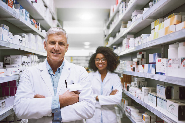 We are the best in what we do. Portrait of two cheerful and confident pharmacist standing with arms folded while looking into the camera in a pharmacy - Fotó, kép