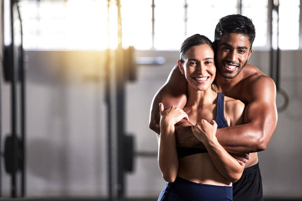 Strong, active and wellness couple looking fit and healthy after workout training session in a gym. Young sexy, attractive and athletic boyfriend and girlfriend hugging after reaching fitness goal. - Photo, image