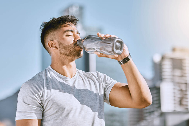 Fitness, healthy thirsty man drinking water while he is exercising outside in sportswear. Runner, cardio workout and active lifestyle for strong athletic body or mental discipline - Foto, Bild