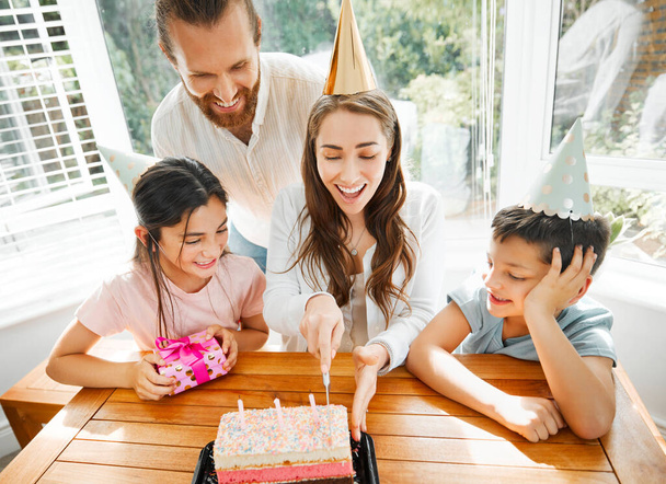 Birthday, cake and celebration with a family celebrating a mother on a special day. Cutting the dessert, having a party and spending time together. Fun, laughter and enjoyment with mom, dad and kids. - Fotó, kép