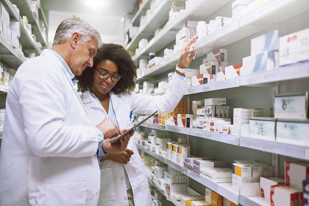 There seems to be enough of this. two focused pharmacist walking around and doing stock inside of a pharmacy - Foto, immagini