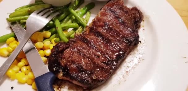 Radost z jedení nejlepšího jídla na světě hovězí steak spolu s kaší brambory s lahodnou houbovou omáčkou a sladkou kukuřicí také zelené fazole podávané v bílém talíři - Záběry, video