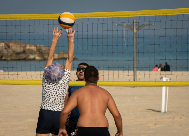 Playing volleyball on the city beach of people of different ages on a clear sunny day. Israel Ashkelon January 2022 - Foto, Bild