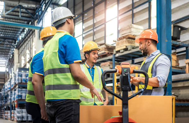 Manager, staff or boss to talking, discussion with worker, employee. Group of people in warehouse, factory with safety helmet, vest. Concept for industry, job, meeting, work training and teamwork. - Photo, Image