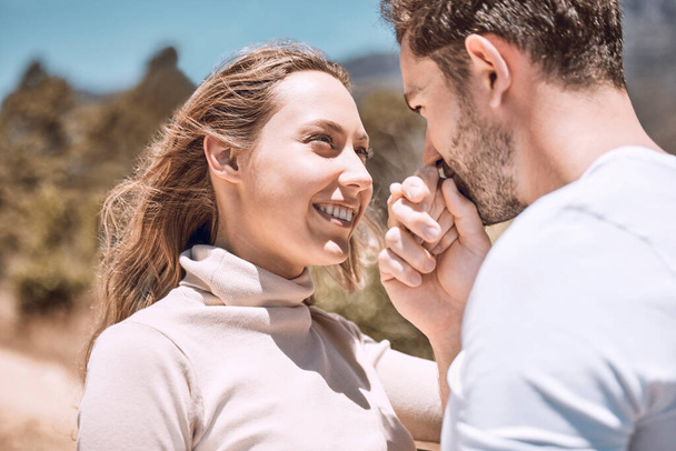 In love, romance and smiling young couple bonding on sunny summer holiday or spring vacation. Hand kissing, cheerful and trendy romantic dating and relationship partners together on getaway trip - Foto, afbeelding