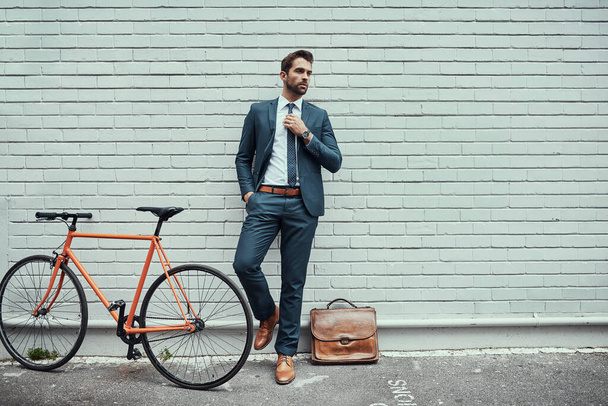 He always cruises stylishly through the streets. a handsome young businessman standing alongside his bike outdoors - Valokuva, kuva