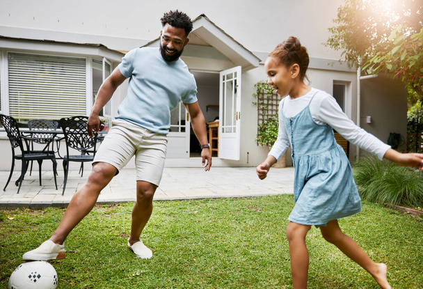 Playing, bonding and having fun in a garden with a smiling father and happy little girl outside. Dad teaching football, learning and showing his daughter how to kick a soccer ball outdoors together. - 写真・画像