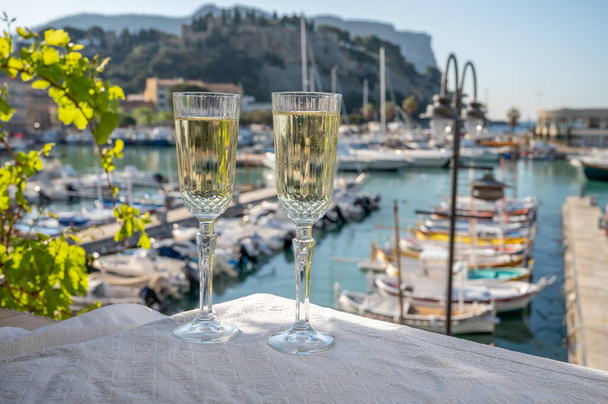 Yazın doğum günü kutlaması iki bardak Fransız şampanyası köpüklü şarap ve renkli balıkçı tekneleriyle Cassis, Provence, Fransa 'daki eski limanda. - Fotoğraf, Görsel