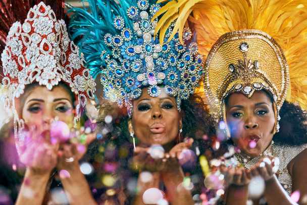 Here to light up your life. beautiful samba dancers blowing confetti from their hands in a carnival - Foto, immagini