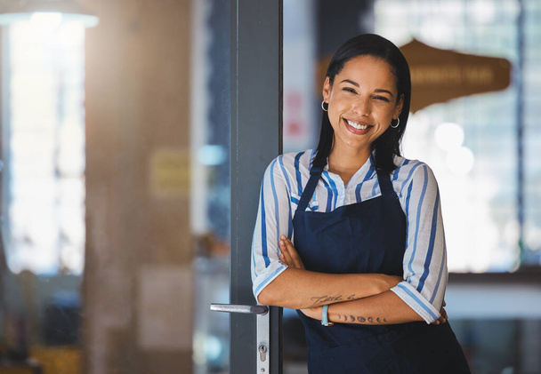 Cafe or coffee shop barista, entrepreneur and female small business owner of successful modern startup or restaurant. Happy, positive and empowered woman leader with welcoming door open for business. - 写真・画像