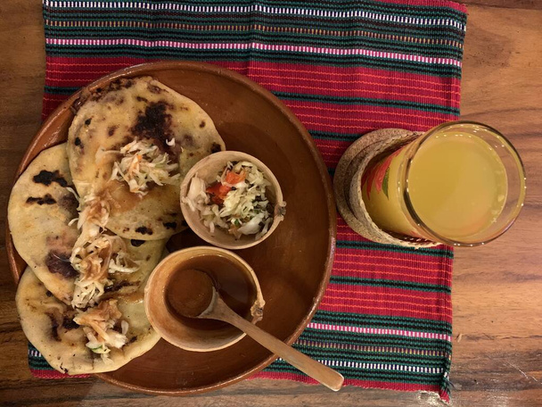 typical Salvadoran dish, cheese pupusas with cabbage and tomato sauce. rice and corn pupusas stuffed with cheese, beans or other ingredients. Orange juice - Foto, immagini