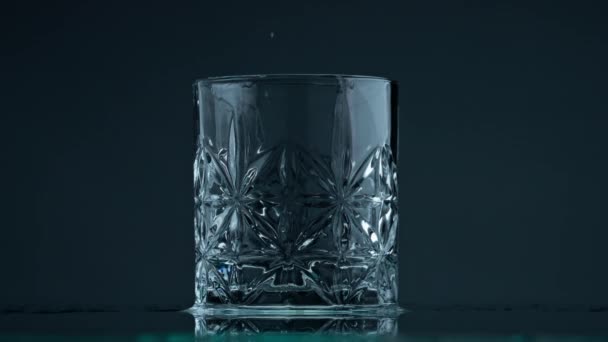 Drinking water rippling glass closeup. Crystal clear droplets falling into jug at gray background. Still transparent liquid waving in beautiful cup. Textured container filling with mineral fluid. - Video, Çekim