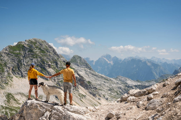 Couple enjoy the view of Slovenian mountains with Russian wolfhound dog - Foto, afbeelding