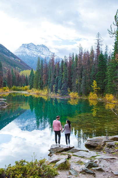 Озеро Яспер Канадські Скелясті гори Альберта Канада, барвисті осінні дерева, що відображені в озері. Кілька азіатських жінок і чоловіків у відпустці в Канаді стоять біля озера з осінніми деревами. - Фото, зображення