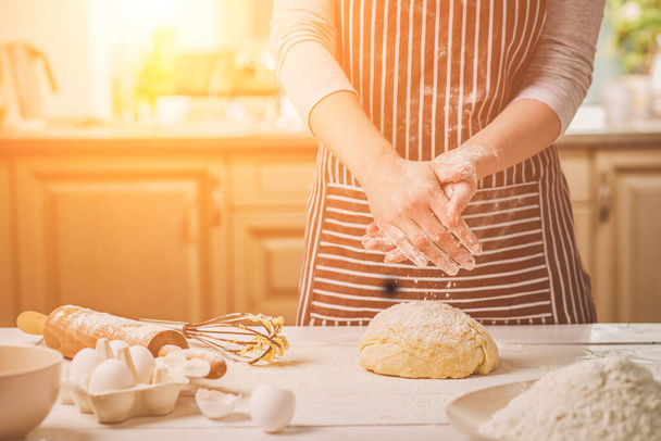 Kobieta slap jego ręce nad zbliżenie ciasta. Kończąc jego piekarnia piekarz wstrząsnąć mąki z jego rąk, ilość wolnego miejsca dla tekstu. Domowe wypieki, proces gotowania - Zdjęcie, obraz