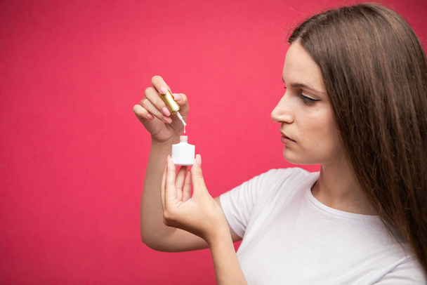 Manicurist showing nail polish, pink background. High quality photo - Photo, image