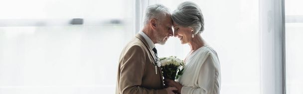 side view of bearded middle aged groom holding wedding bouquet with happy bride in white dress, banner - Fotoğraf, Görsel