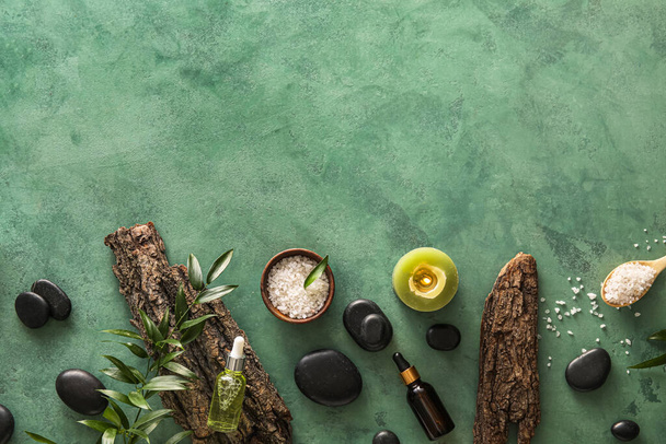 Composition with bottles of essential oil, spa stones, tree bark and sea salt on color background - Zdjęcie, obraz