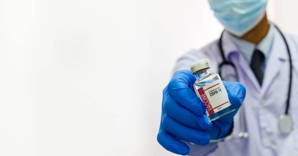 Чоловік лікар в уніформі медичних рукавичок, що тримає пляшку ковадла 19 вірусу вакцини на білому фоні. копіювальний простір
. - Фото, зображення
