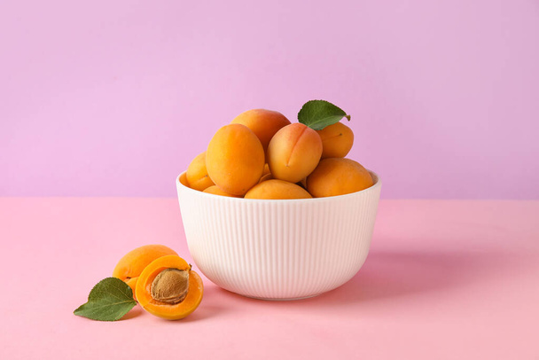 Bowl of delicious apricots on color background - Fotó, kép