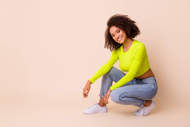 Full length photo of lovely young lady curly hair new clothes shop banner dressed stylish yellow look isolated on beige color background. - Φωτογραφία, εικόνα