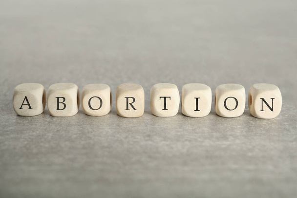 Word Abortion made of wooden cubes on grey table, closeup - Foto, Imagen