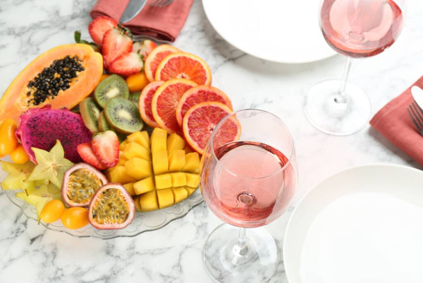 Delicious exotic fruits and wine on white table - Foto, Imagen