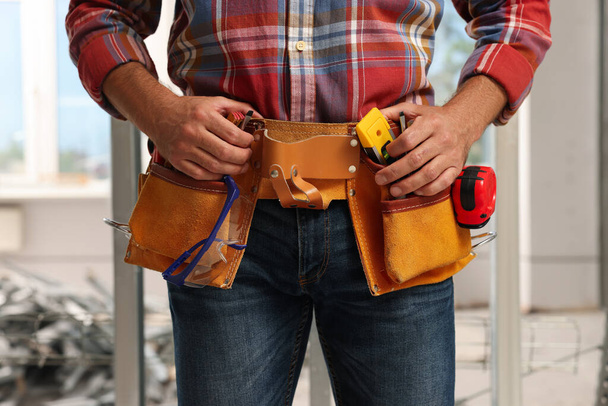 Professional builder with tool belt indoors, closeup - Foto, Imagem