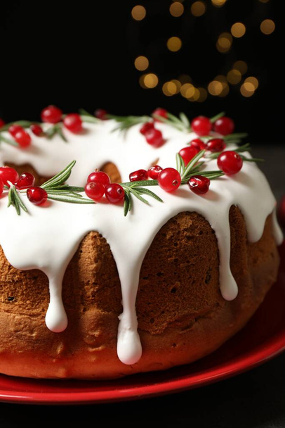 Traditional Christmas cake decorated with glaze, pomegranate seeds, cranberries and rosemary, closeup - Фото, изображение