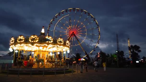 KOBULETI, GEORGIA - July 22, 2022: Ride Carousel Quickly rotates at sunset children's vintage. Horses and animals swing and entertain children. Swinging amusement fair in amusement park at dusk. - Felvétel, videó