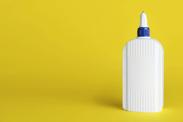 Bottle of glue on yellow background, space for text - Foto, imagen