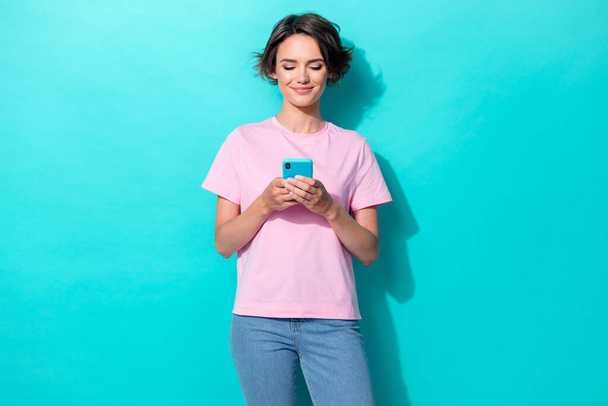 Photo of funky bob hair young lady look telephone wear pink t-shirt jeans isolated on turquoise color background. - Foto, Bild