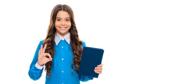 Happy primary school pupil hold library book showing OK sign isolated on white, knowledge day. Horizontal isolated poster of school girl student. Banner header portrait of schoolgirl copy space - Foto, Bild