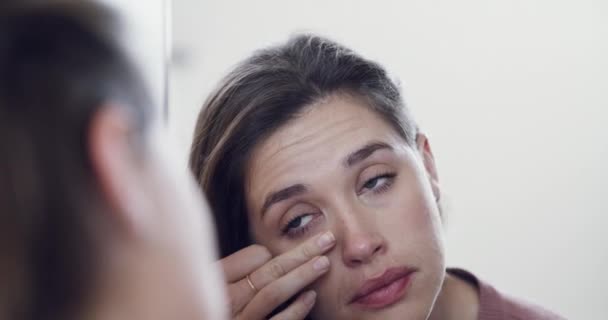 Sad, unhappy and depressed female wipe tears after crying, facing loss or mental health issue. Closeup mirror reflection portrait of woman feeling upset, going through difficult time of trouble - Filmati, video