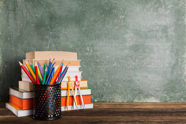 a Stack of books and stationery on the background of the school board. Education and back to school concept. - 写真・画像