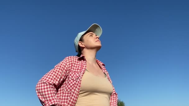 Young adult woman enjoying clear blue sky, standing at meadow field with outstretched hands at sunrise. Cheerful woman expressing positive emotions outdoors. Freedom, hope concept - Metraje, vídeo