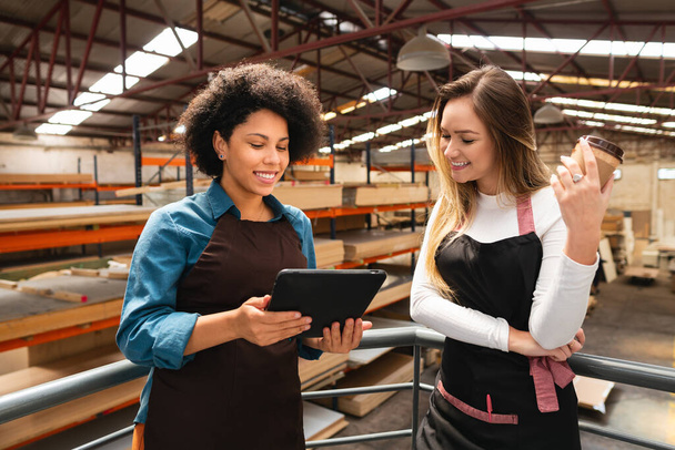african american woman showing tablet to female colleague at storehouse - Foto, Imagem