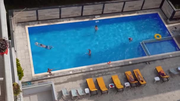 Antenna of friends having fun in pool. Happy young people relax in luxury resort on sunny day. View from above. Girls in bikinis sunbathe in sun. - Video, Çekim