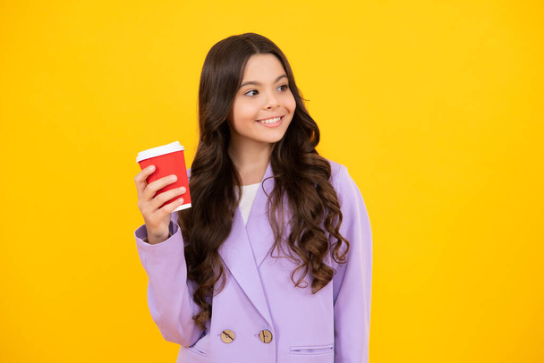 Child with coffee or tea cup isolated on yellow studio background. Teenage girl with take away beverage. Happy face, positive and smiling emotions of teenager girl - Foto, Bild