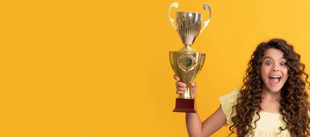 amazed kid holding golden champion cup and shampoo bottle, hair care. Horizontal poster of isolated child face, banner header, copy space - Photo, Image