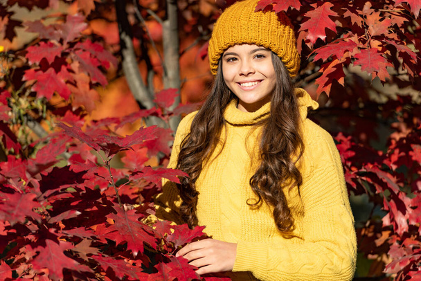 smiling teen kid in hat at autumn leaves on natural background. - Photo, Image