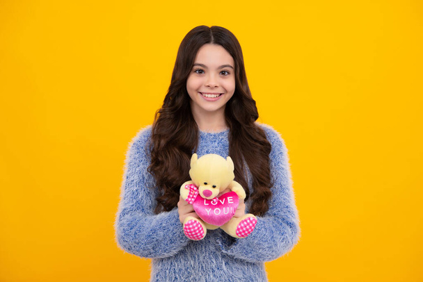 Teen girl child in casual wear holding plush toy isolated on yellow background, happy childhood. Happy teenager, positive and smiling emotions of teen girl - Foto, imagen