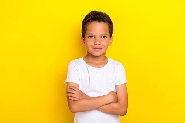 Photo of calm serious school boy dressed trendy white clothes outfit arm crossed isolated on yellow color background. - Foto, Imagem