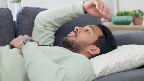 Upset, frustrated and sad young male lying, thinking and contemplating on a living room couch. Depressed man lounge on a sofa feeling unhappy, guilty and struggling with mental health indoors. - Materiaali, video