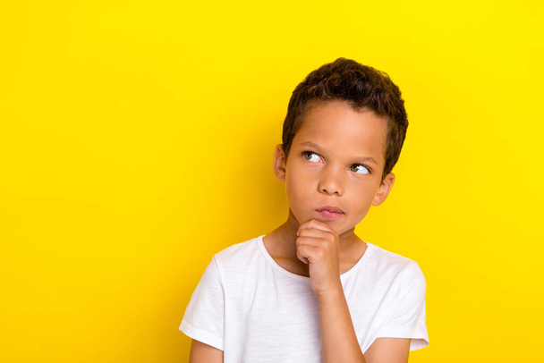 Photo of minded little boy person look empty space arm touch face cosider question uncertain unsure isolated on yellow color background. - 写真・画像