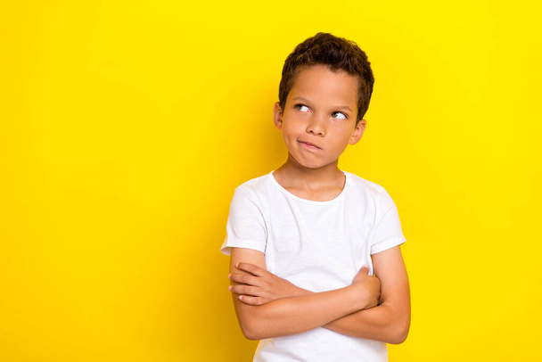 Photo of uncertain unsure boy arm folded decide consider question interested look empty space isolated on yellow color background. - Foto, Imagem
