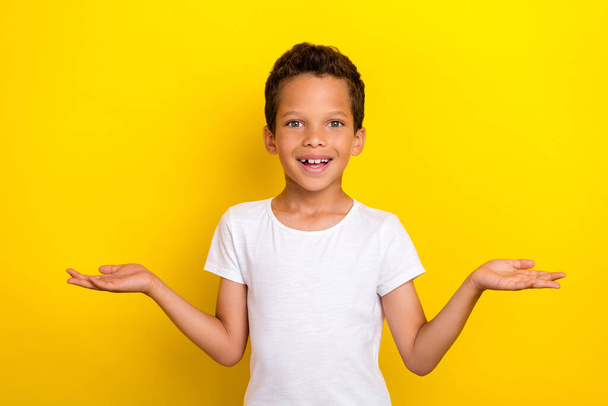 Photo of funky small boy hold empty space wear white t-shirt isolated on yellow color background. - Foto, Bild